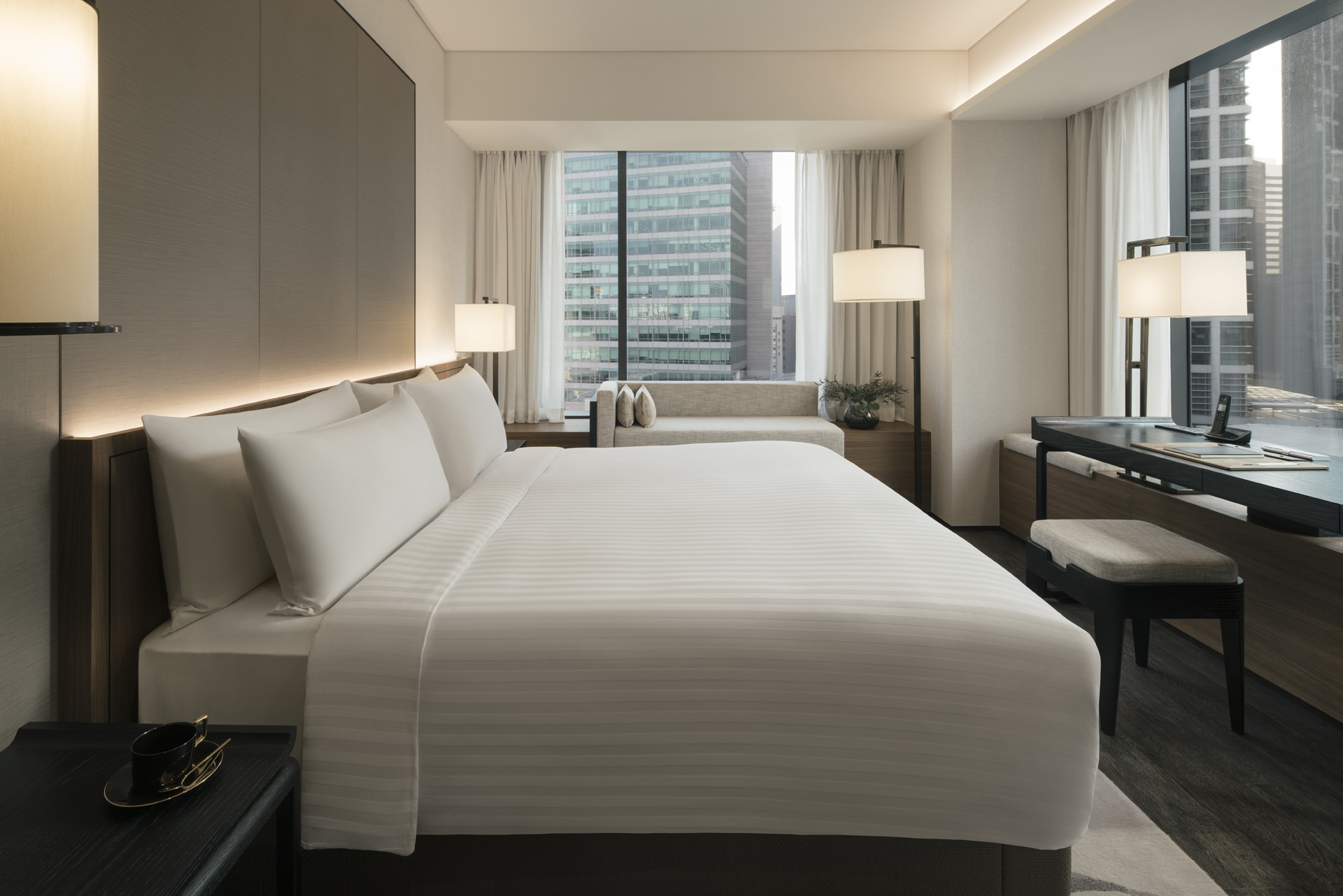 Modern luxury guest room at The Clan Hotel with floor-to-ceiling windows overlooking Singapore's heritage shophouses